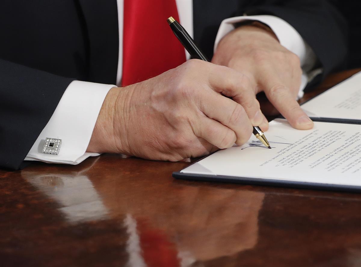 President Donald Trump signs an executive order in the Oval Office of the White House in Washington. Friday, Feb. 3, 2017. (AP Photo/Pablo Martinez Monsivais)
