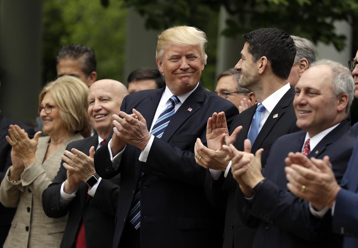 President Donald Trump, flanked by House Ways and Means Committee Chairman Rep. Kevin Brady, R-Texas, and House Speaker Paul Ryan of Wis., applaud in the Rose Garden of the White House in Washington, Thursday, May 4, 2017, after the House pushed through a health care bill. (AP Photo/Evan Vucci)