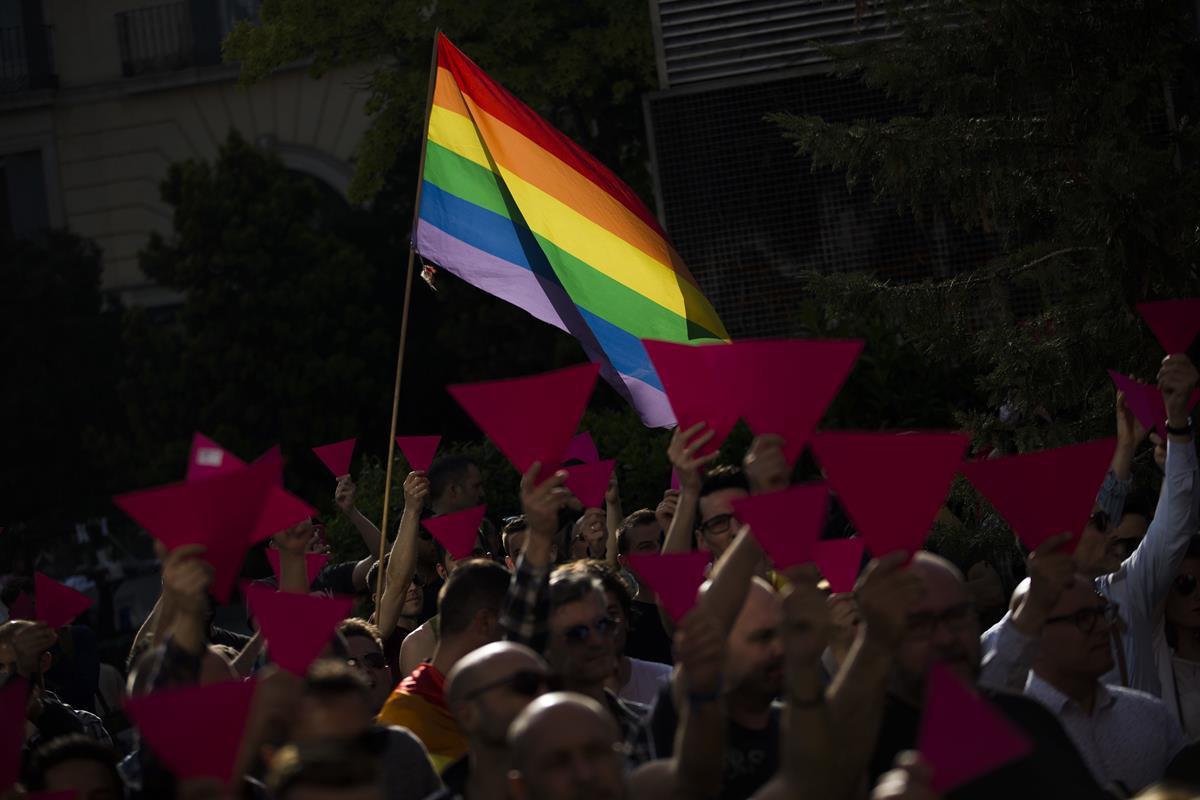 People hold up pink cardboard triangles and wave a rainbow flag during a gathering in support to the LGBT community in the Russian region of Chechnya, in Madrid, Tuesday, April 25, 2017. (AP Photo/Francisco Seco)