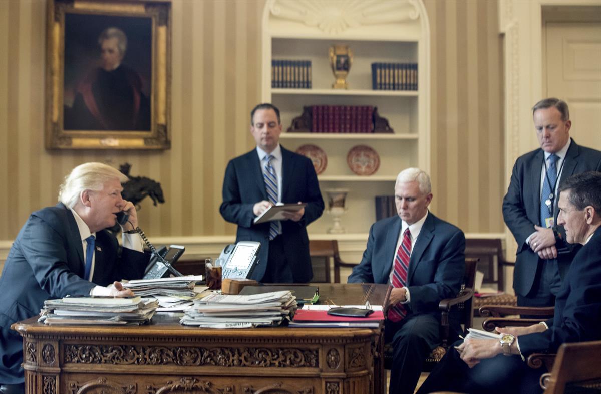President Donald Trump, accompanied by, from second from left, Chief of Staff Reince Priebus, Vice President Mike Pence, White House press secretary Sean Spicer and former National Security Adviser Michael Flynn, speaks on the phone with Russian President Vladimir Putin, Saturday, Jan. 28, 2017, in the Oval Office at the White House in Washington. (AP Photo/Andrew Harnik)