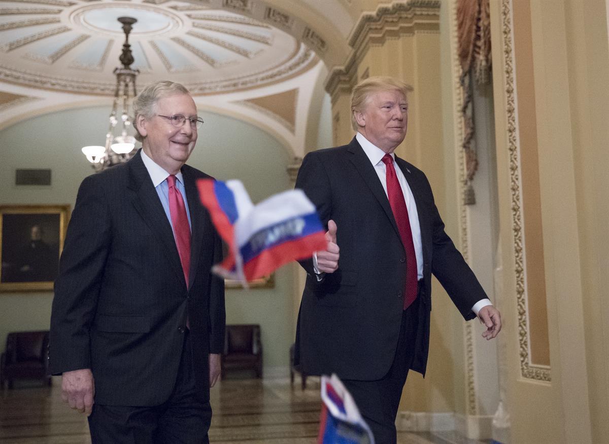 Small Russian flags with the word “Trump” written on them are thrown by a protester as President Donald Trump, escorted by Senate Majority Leader Mitch McConnell, R-Ky., arrives on Capitol Hill to have lunch with Senate Republicans and push for his tax reform agenda, in Washington — Tuesday, Oct. 24, 2017 (AP Photo/J. Scott Applewhite)