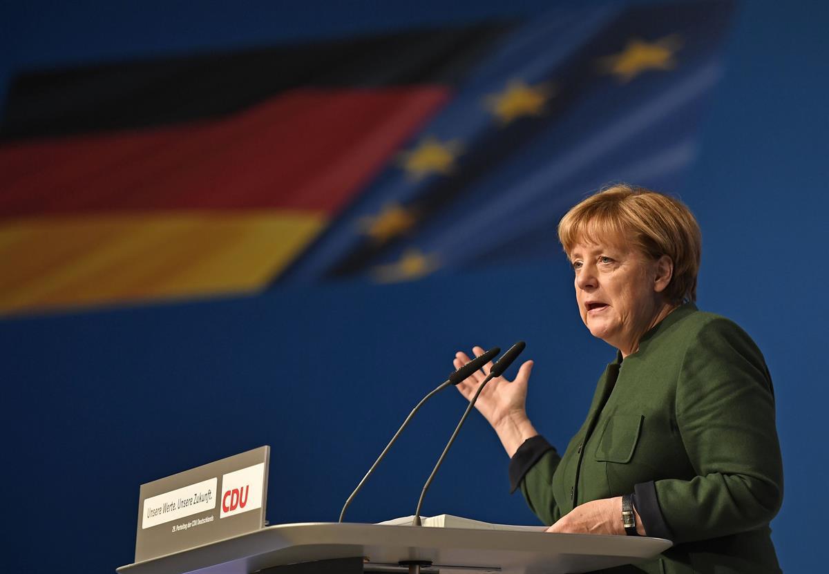 German chancellor Angela Merkel speaks in front of the national flag at the general party conference of the Christian Democratic Union, CDU, in Essen, Germany, Wednesday, Dec. 7, 2016. (AP Photo/Martin Meissner)