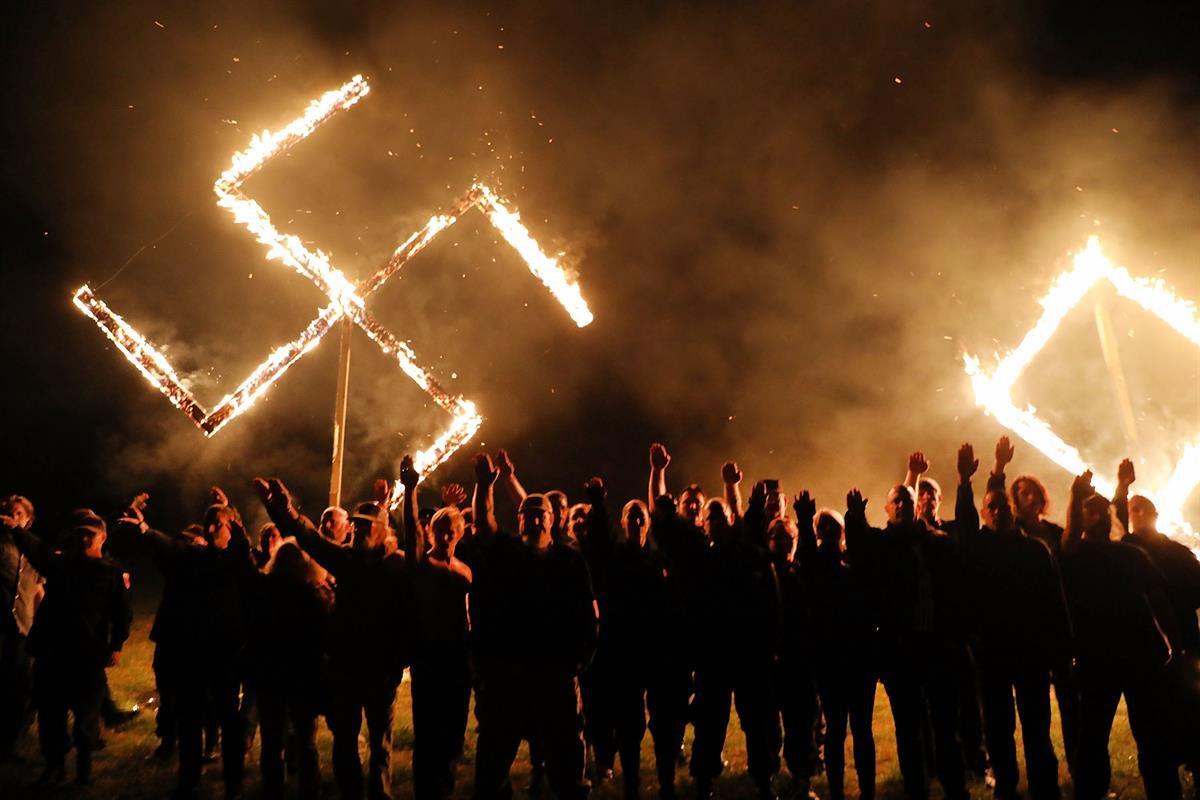 Members of the National Socialist Movement, one of the largest neo-Nazi groups in the US, hold a swastika burning after a rally on April 21, 2018 in Draketown, Georgia (Spencer Platt — Getty Images)